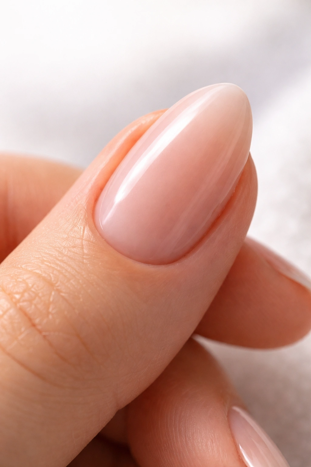 Close-up of a smooth, buffed short almond nail ready for bright color.