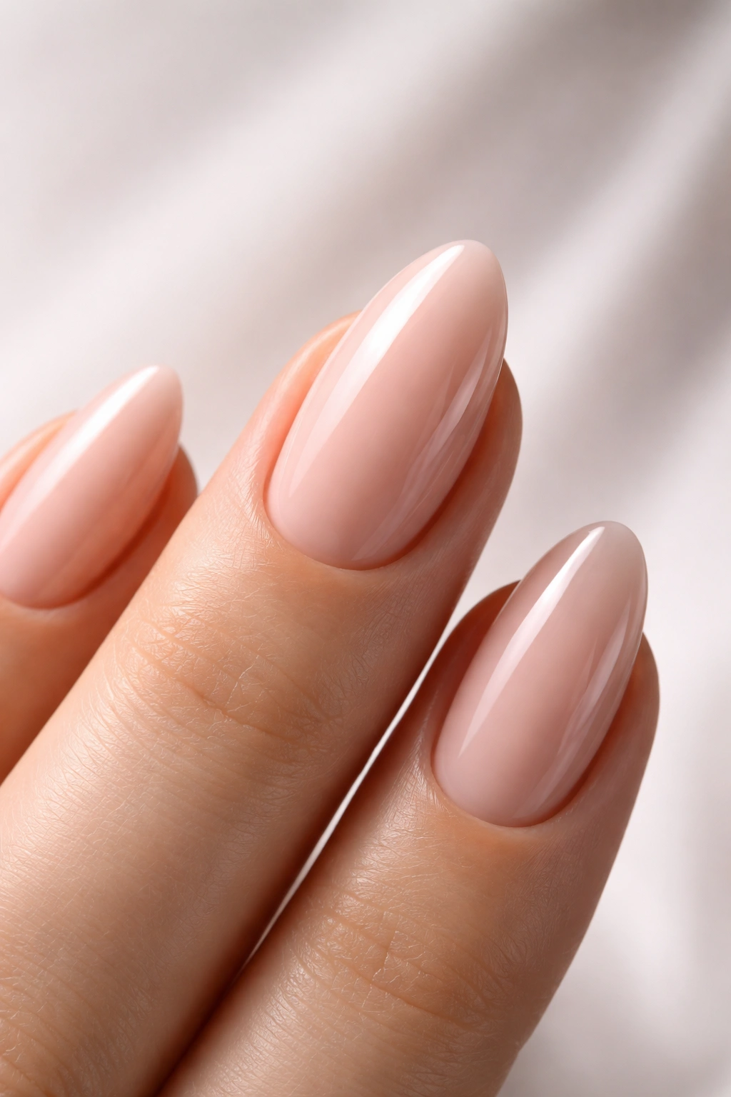 Close-up of an almond-shaped nail on a manicured hand in a neutral studio setting