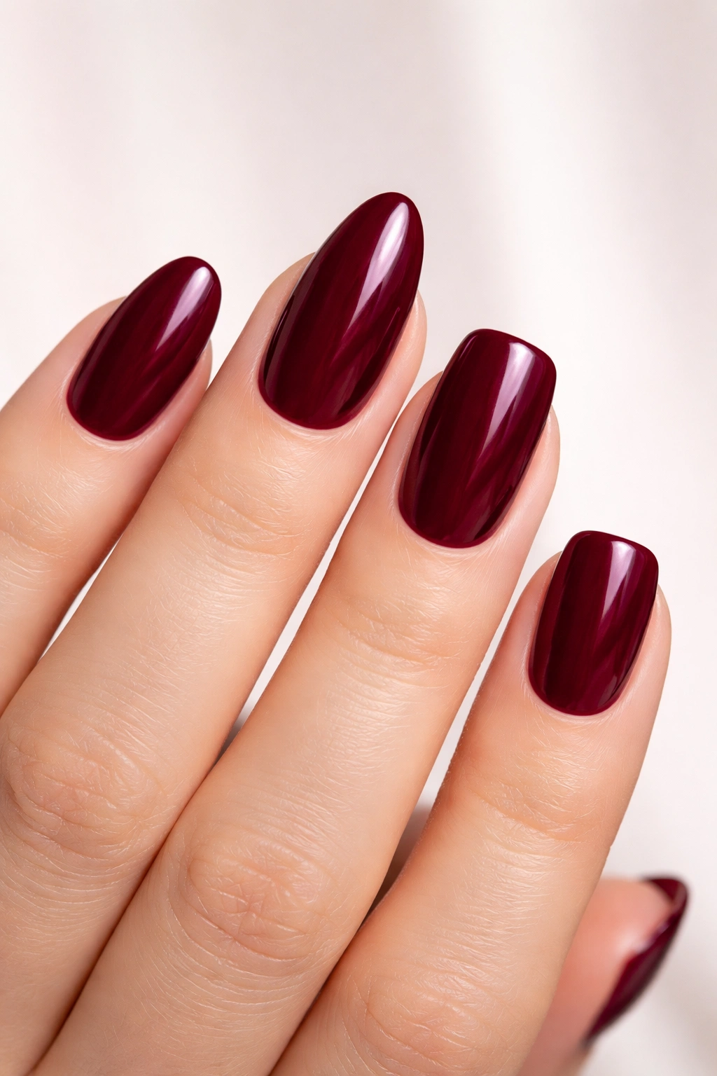 Nails in oval, almond, and squoval shapes with burgundy polish