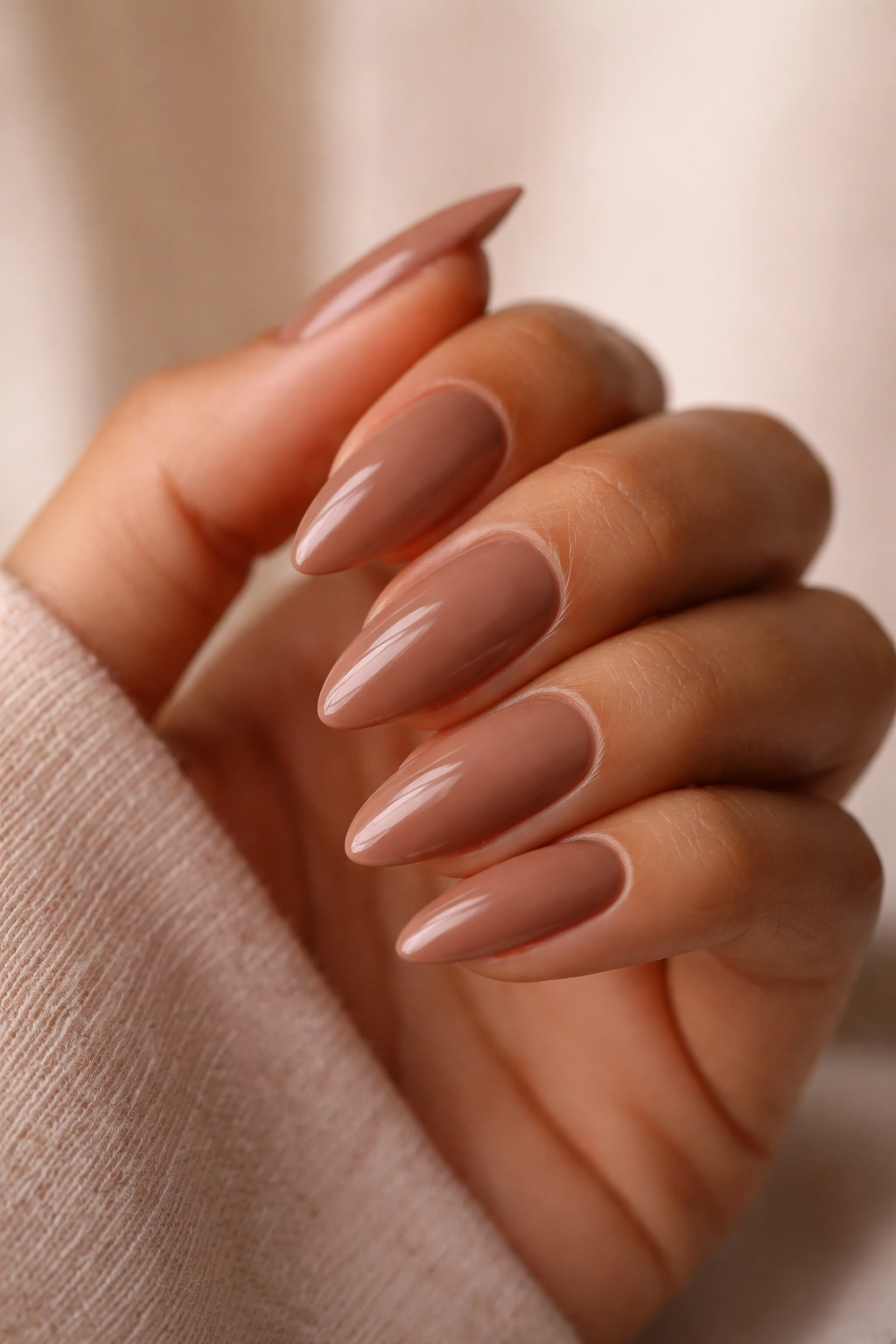 Close-up of almond nails in soft brown nude with warm depth