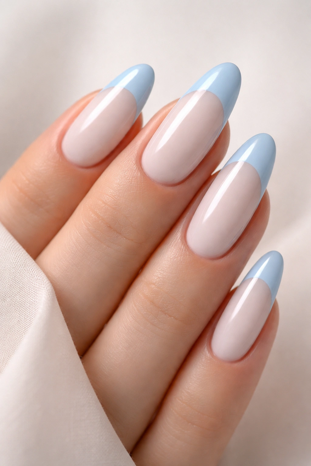 Close-up of long oval nails with pale dusty blue tips on white base