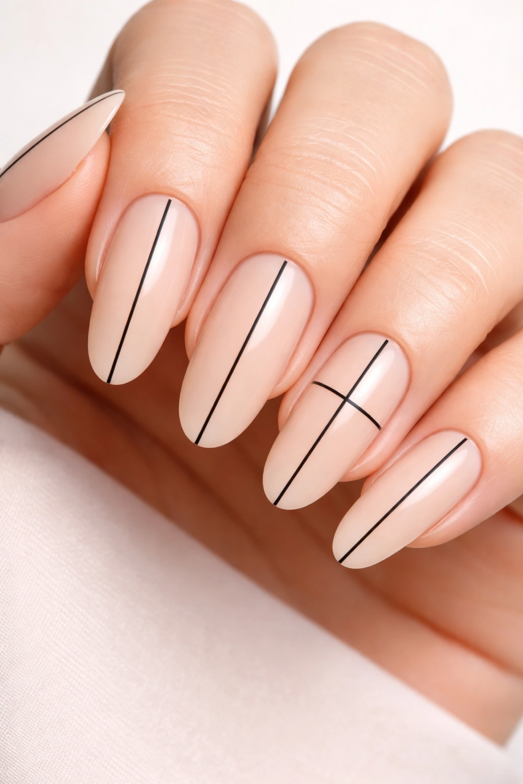 Long round nails with nude base and black line design including a cross on accent nail