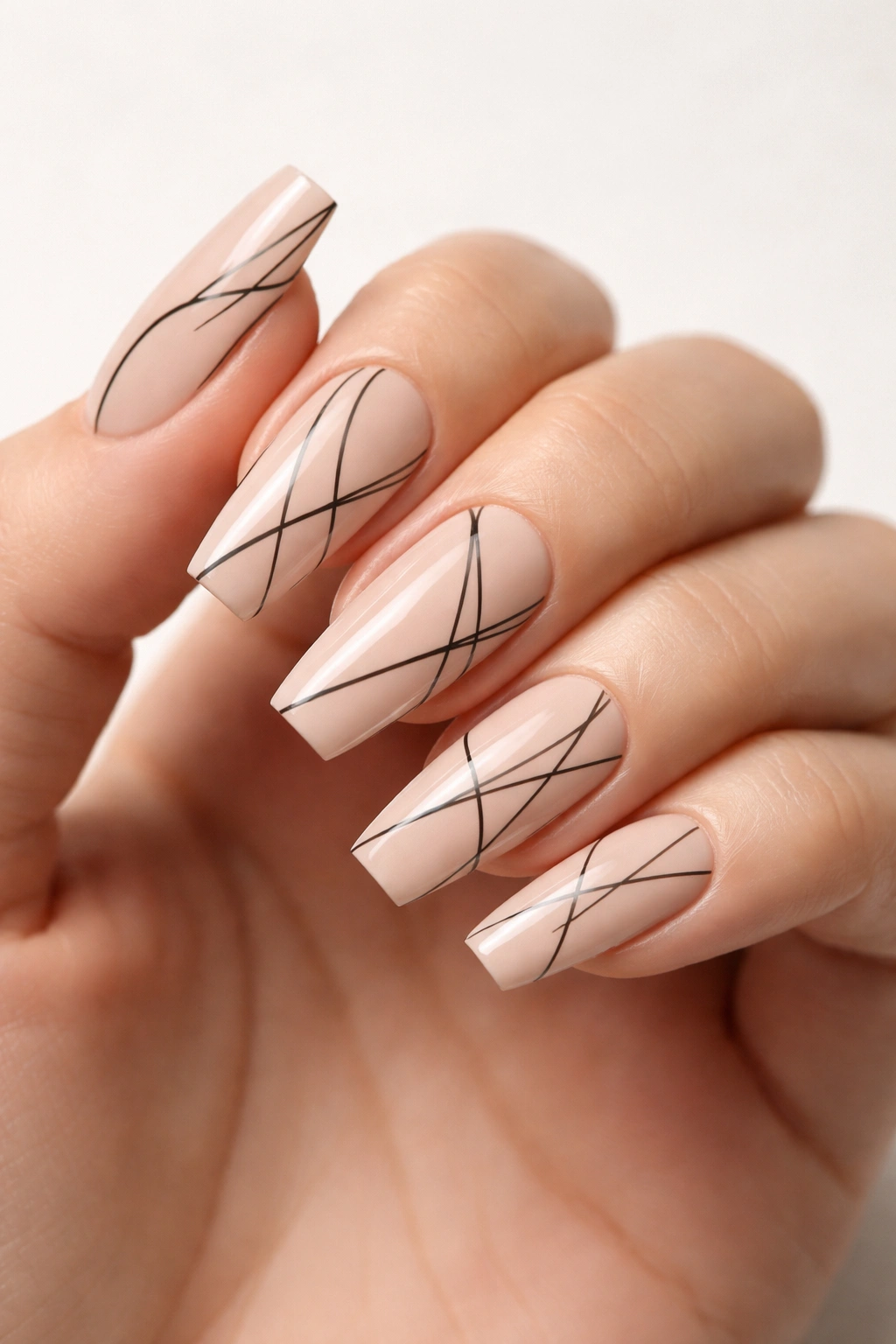 Close-up of nude coffin nails with minimalist black line work