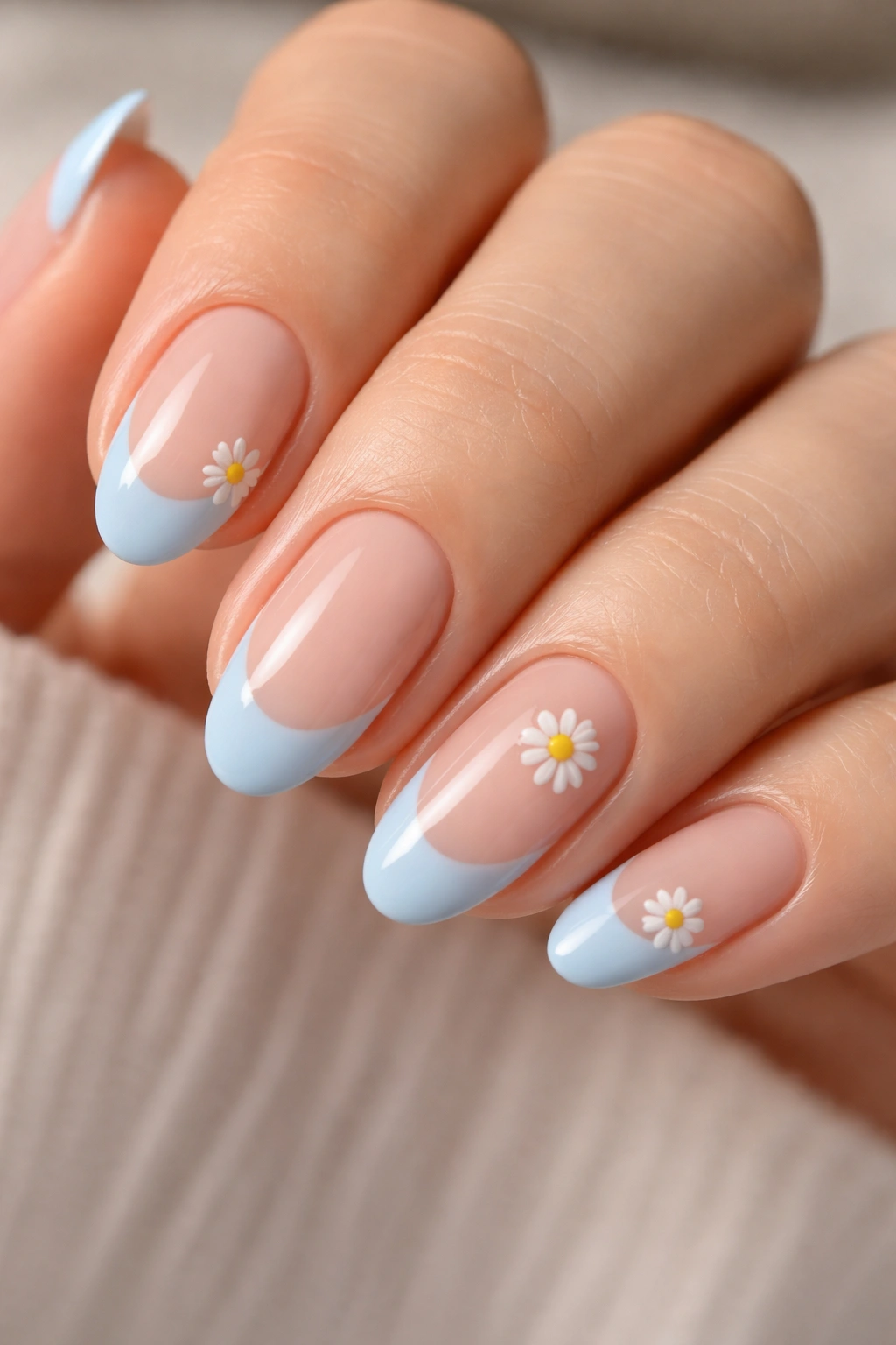 Close-up of short almond nails with blue tips and a tiny white daisy accent