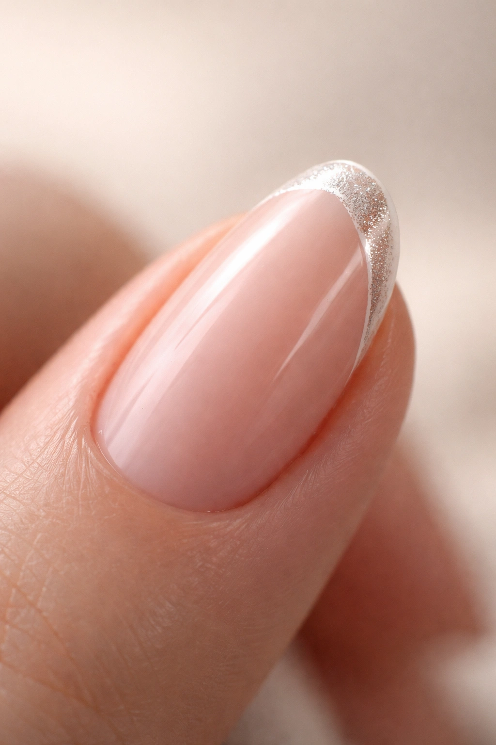 Close-up of a short almond nail with an ultra-thin white line and chrome dust on the tip