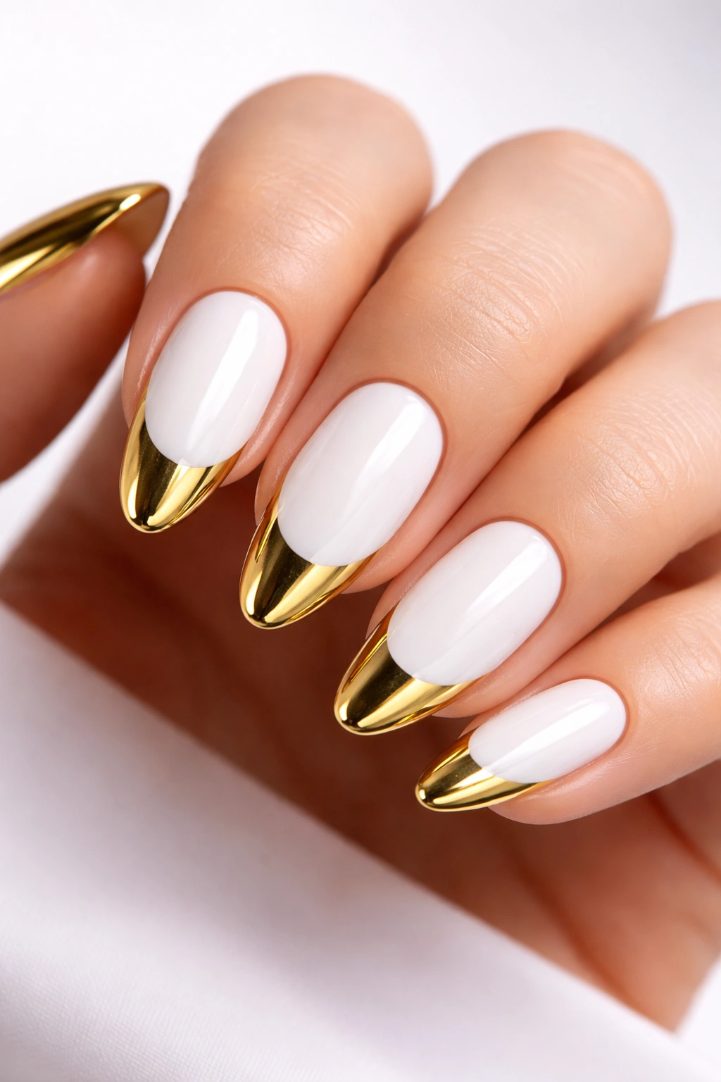 Nails with gold chrome tips on white base reflecting light