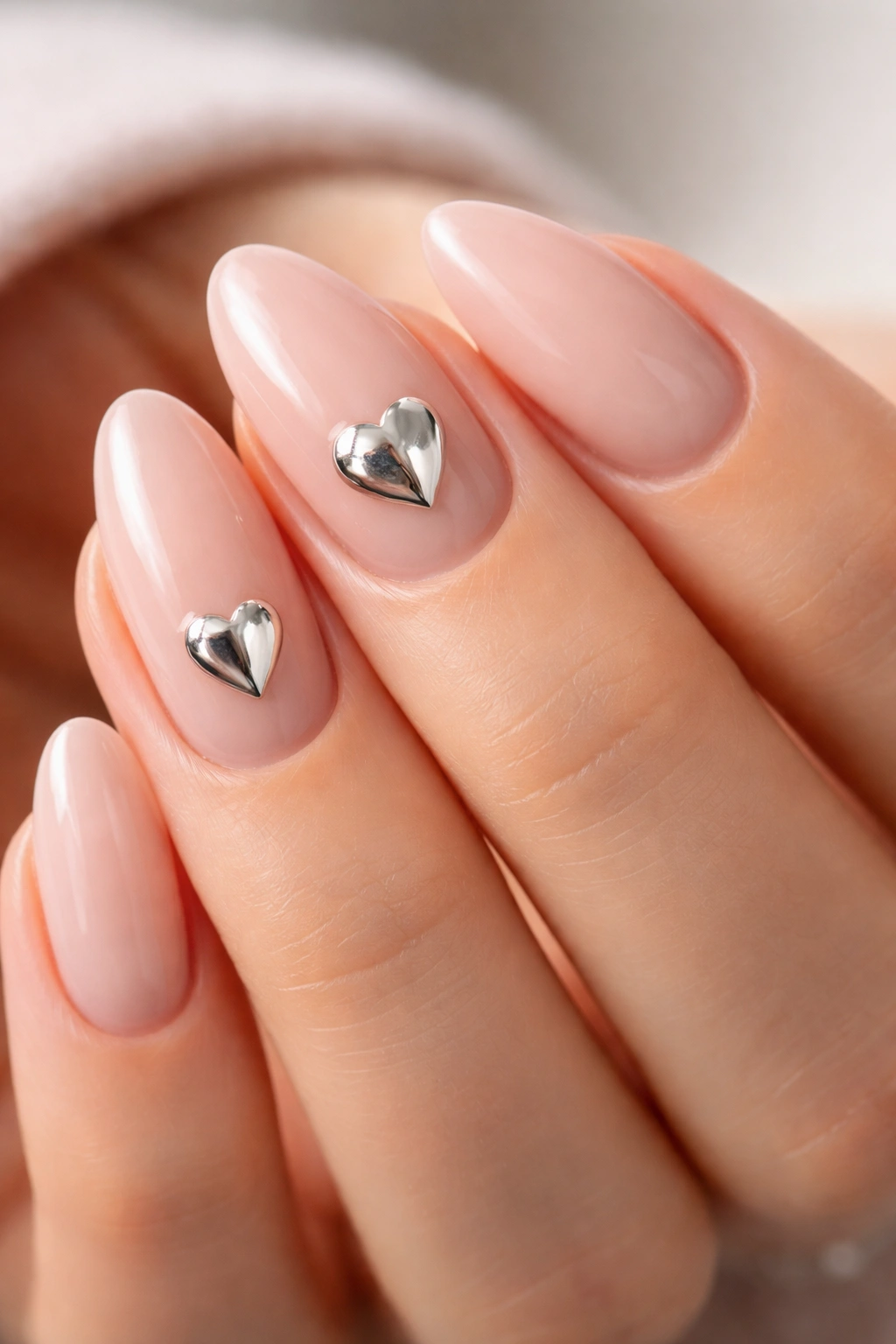 Close-up of short almond nails with pale base and chrome mirror hearts