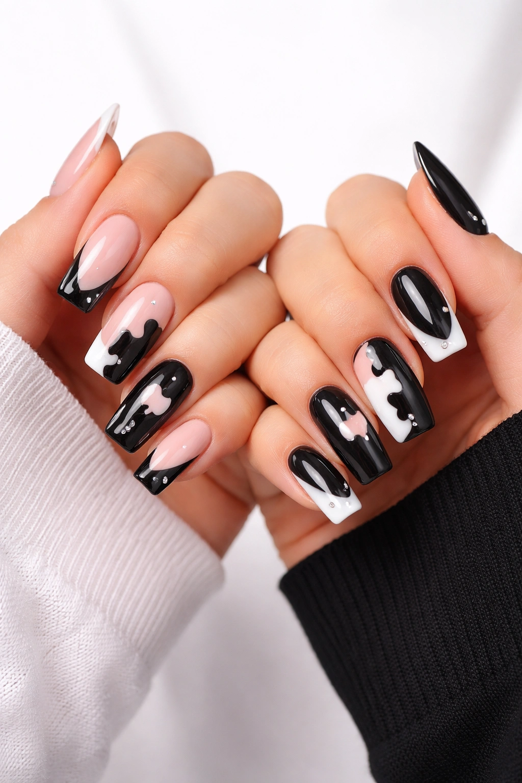 Two hands with matching puzzle-piece nail designs in contrasting light and dark schemes