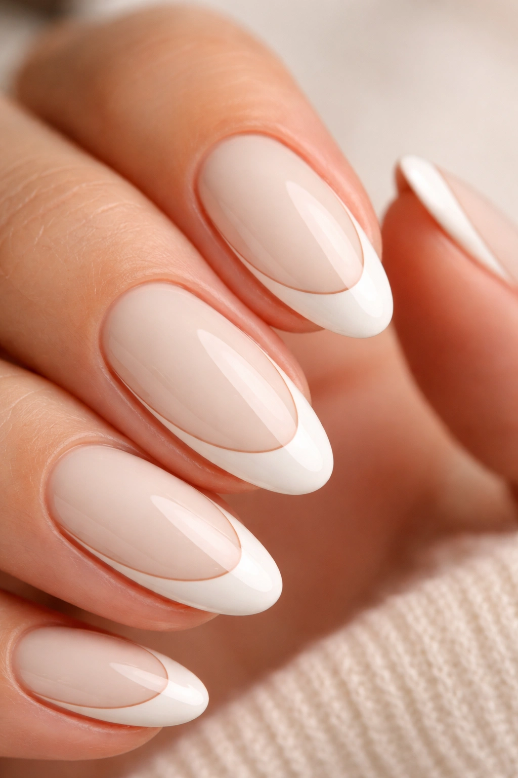 Close-up of a short almond nail with cream base, white smile line and tan outline