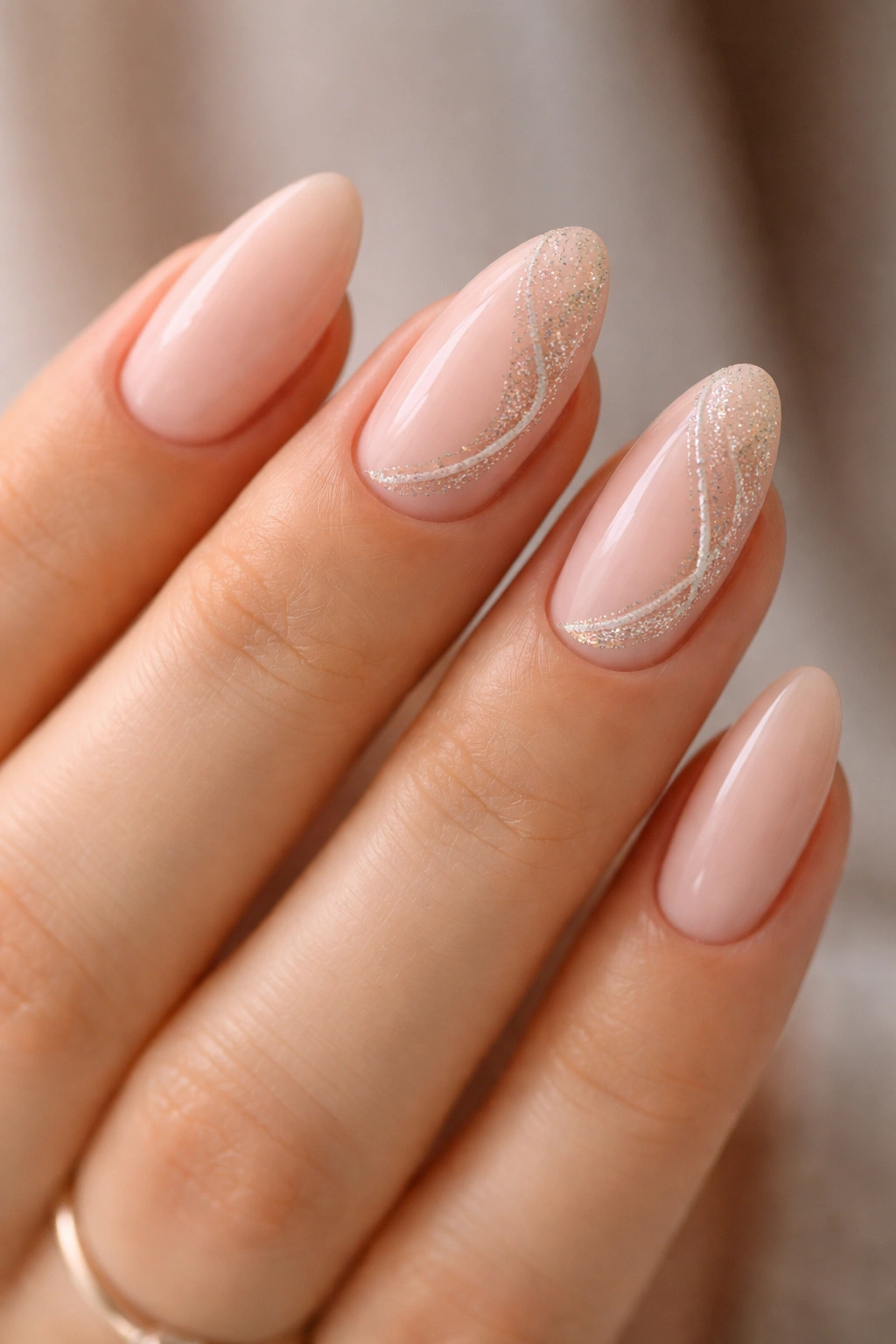 Close-up of short almond nails with glitter swirl accent on nude base