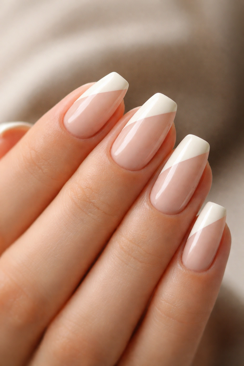 Close-up ivory short ballerina nails with a diagonal tip on a nude base
