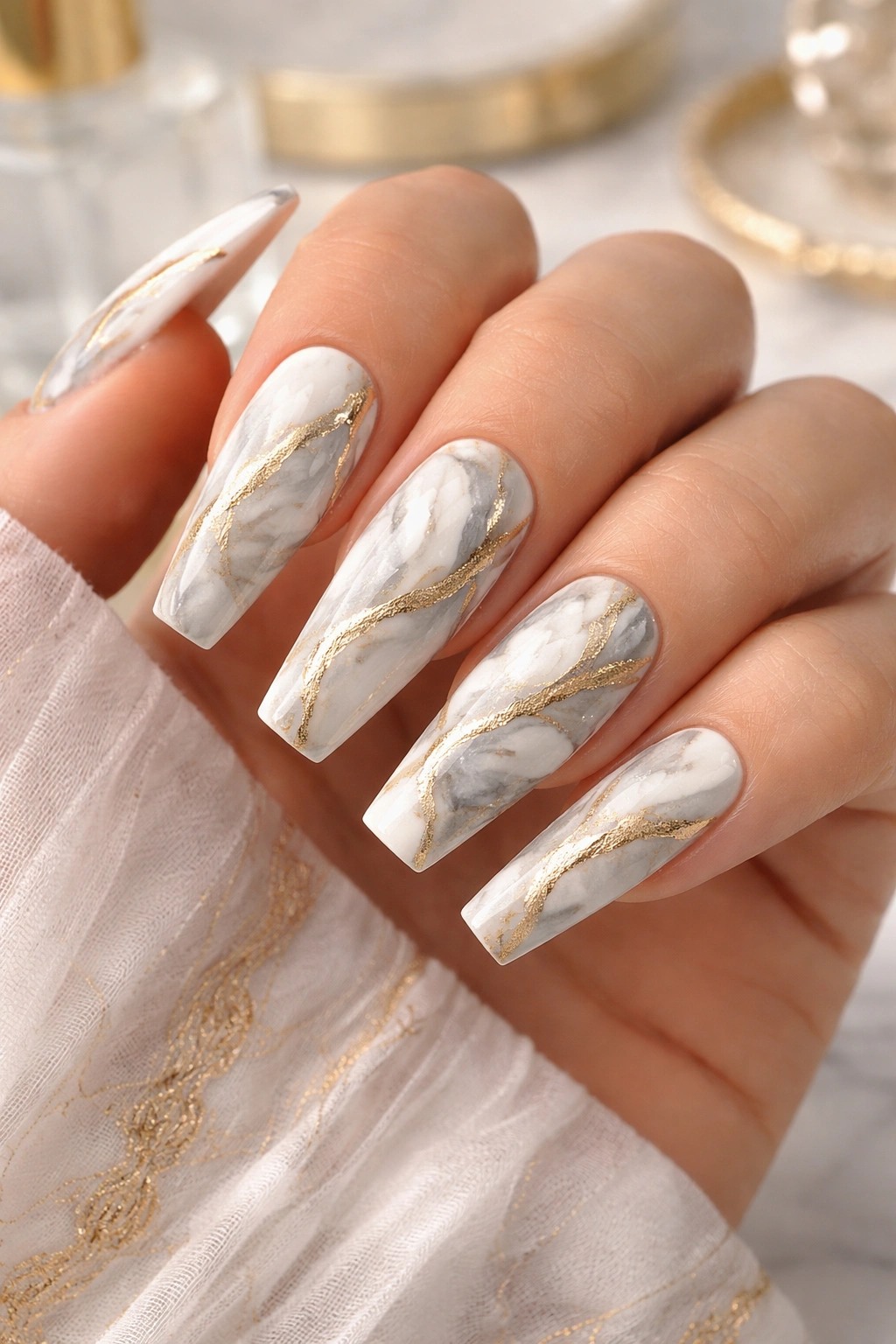 Nails with white and gray marble swirls and gold veining