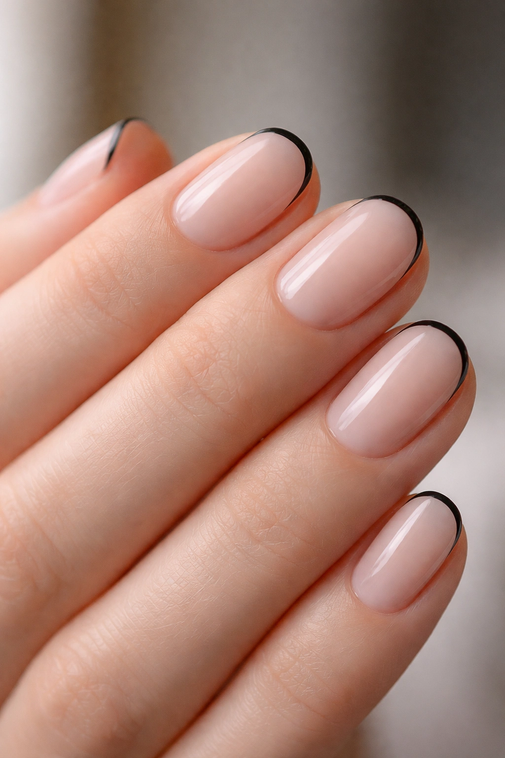 Close-up of very short oval nails with micro black tips on a sheer base
