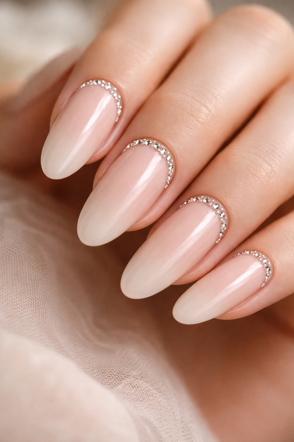 Milky nude long oval nails with a cuticle crescent of clear stones
