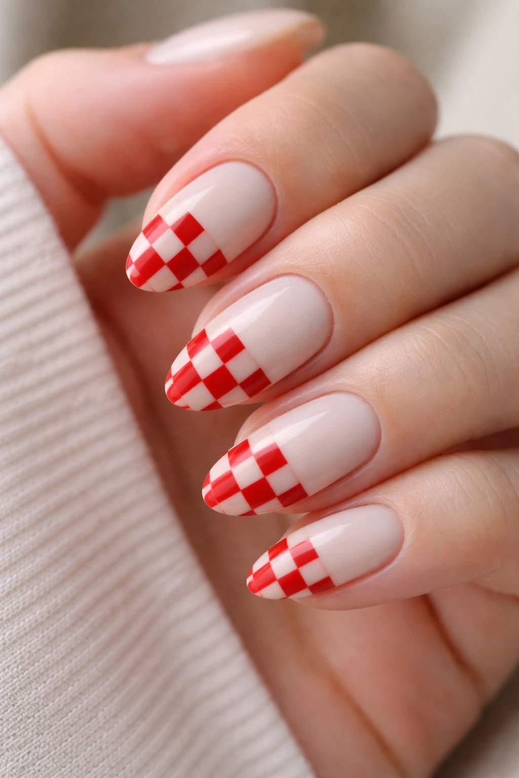 Short almond nails with cherry red checker patterns on a milky white base