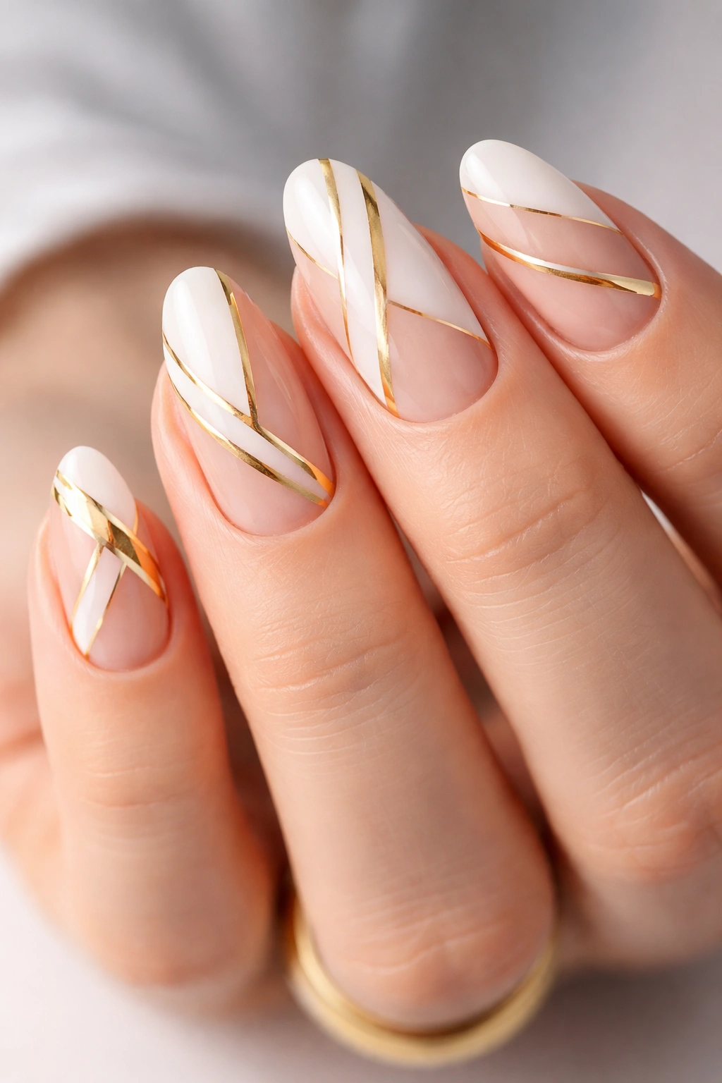 Nails with white geometric shapes and gold lines on natural nail