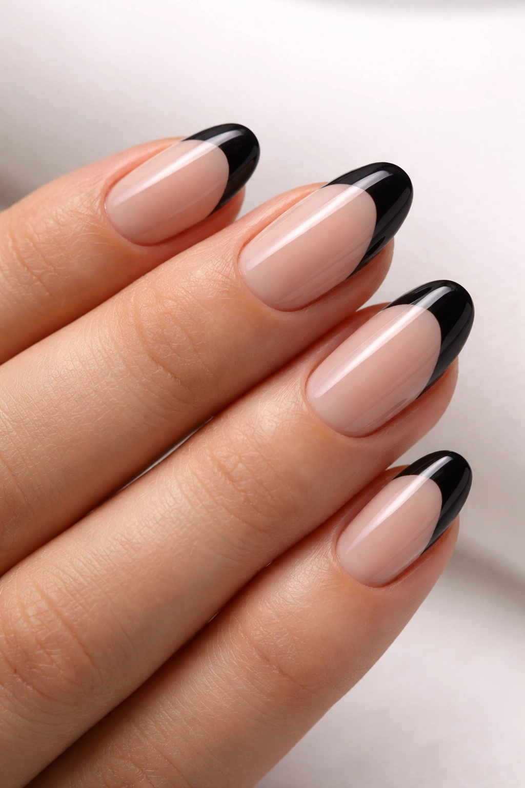 Close-up of short oval nails with black tips and negative space design