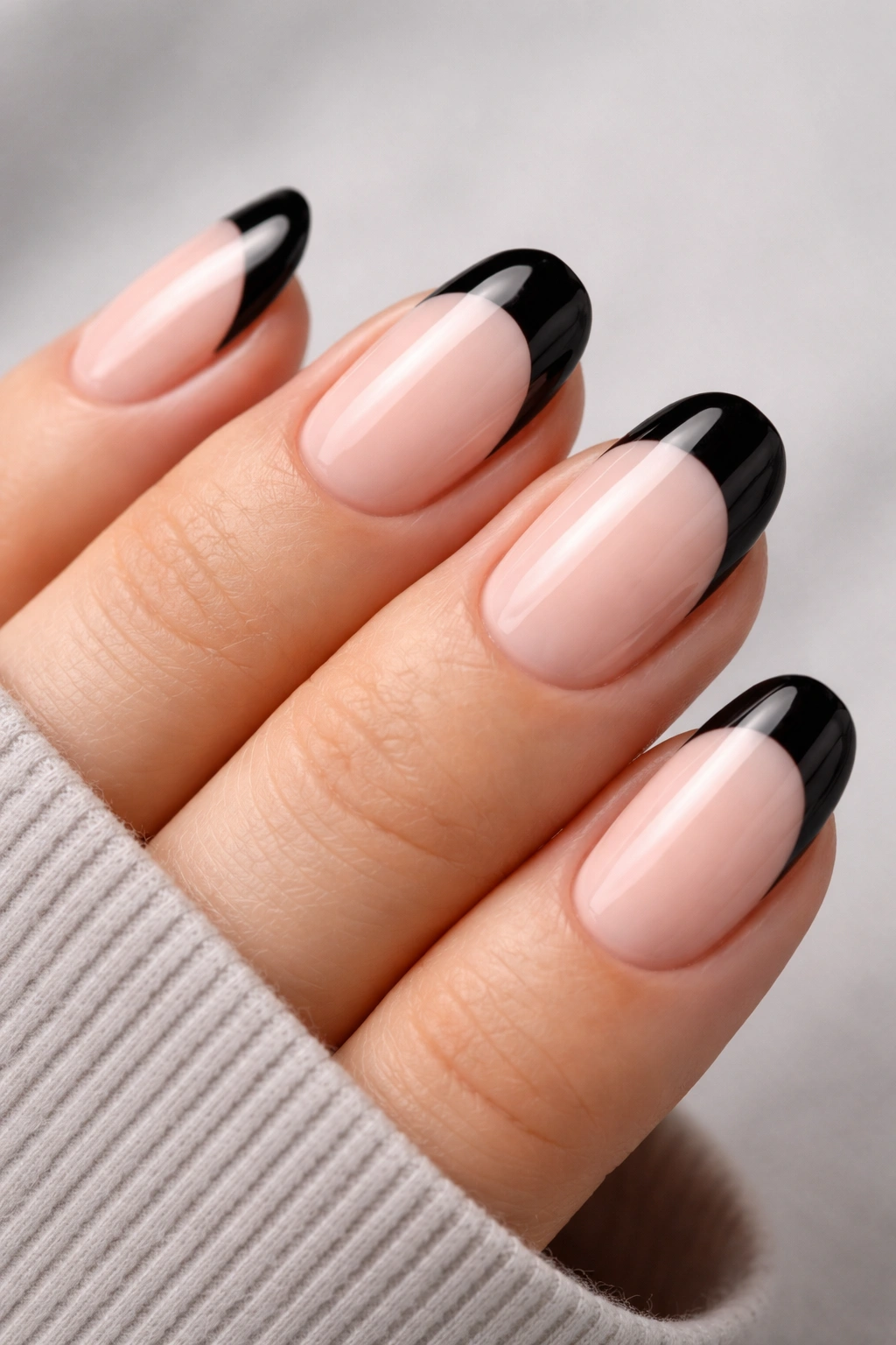 Close-up of short oval nails with thick black tips on a pale base