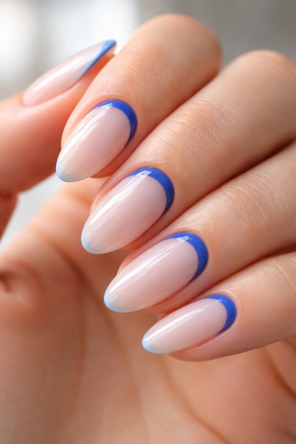 Close-up of reverse French blue crescent at base on short almond nail