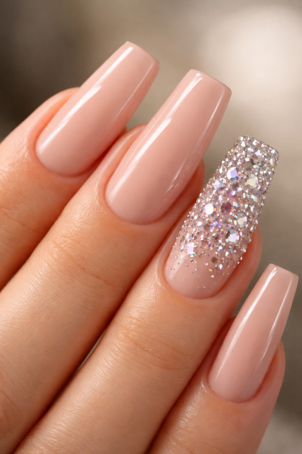 Close-up of nude manicure with rhinestone-accent nail featuring AB and clear stones