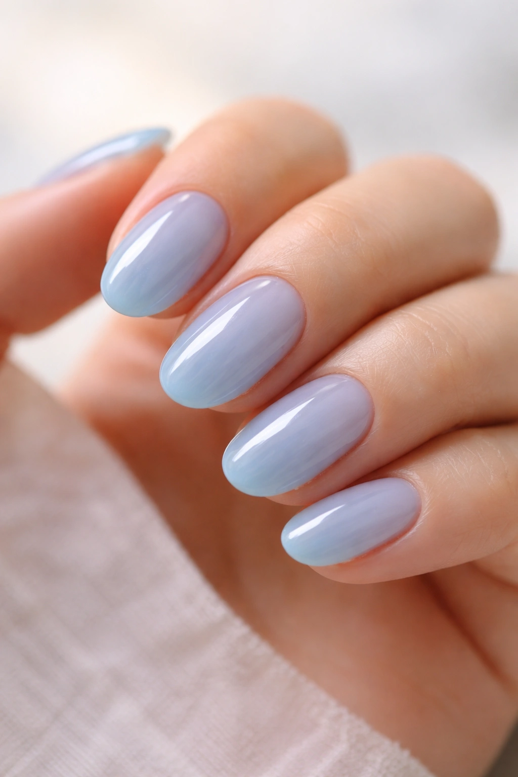 Close-up of short oval nails with sky blue jelly polish showing translucency