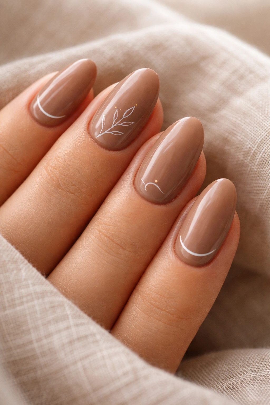 Close-up of soft brown nails with minimal line art on short almond shape