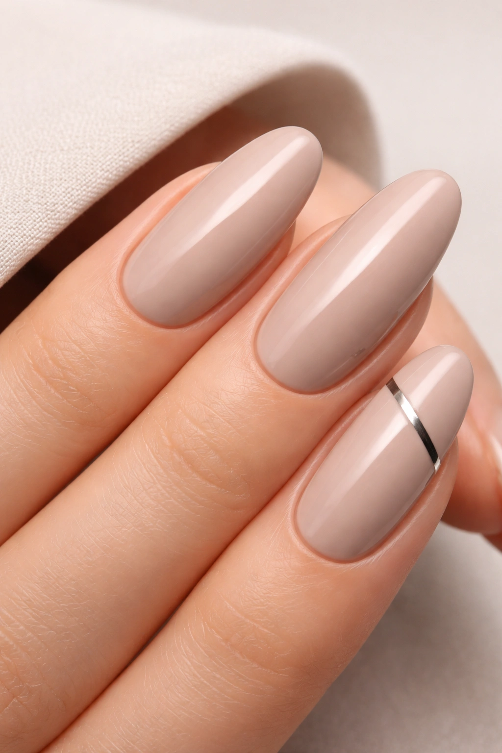 Oval nails in soft taupe with a small geometric edge accent