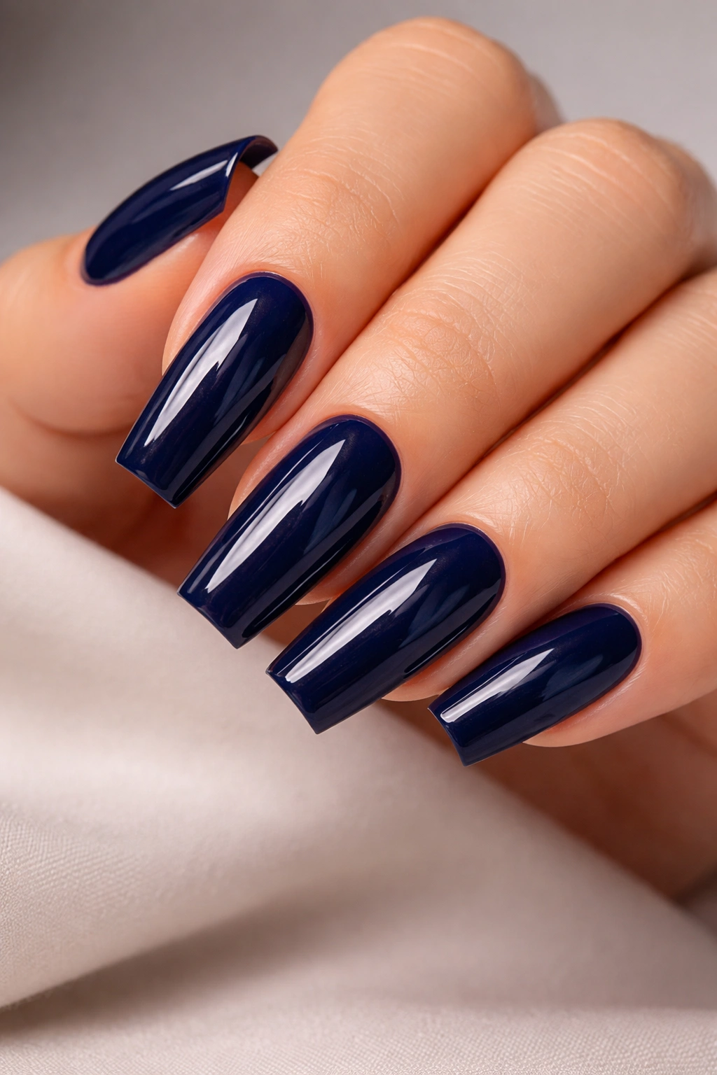 Close-up of glossy navy blue acrylic nails with a high-gloss finish