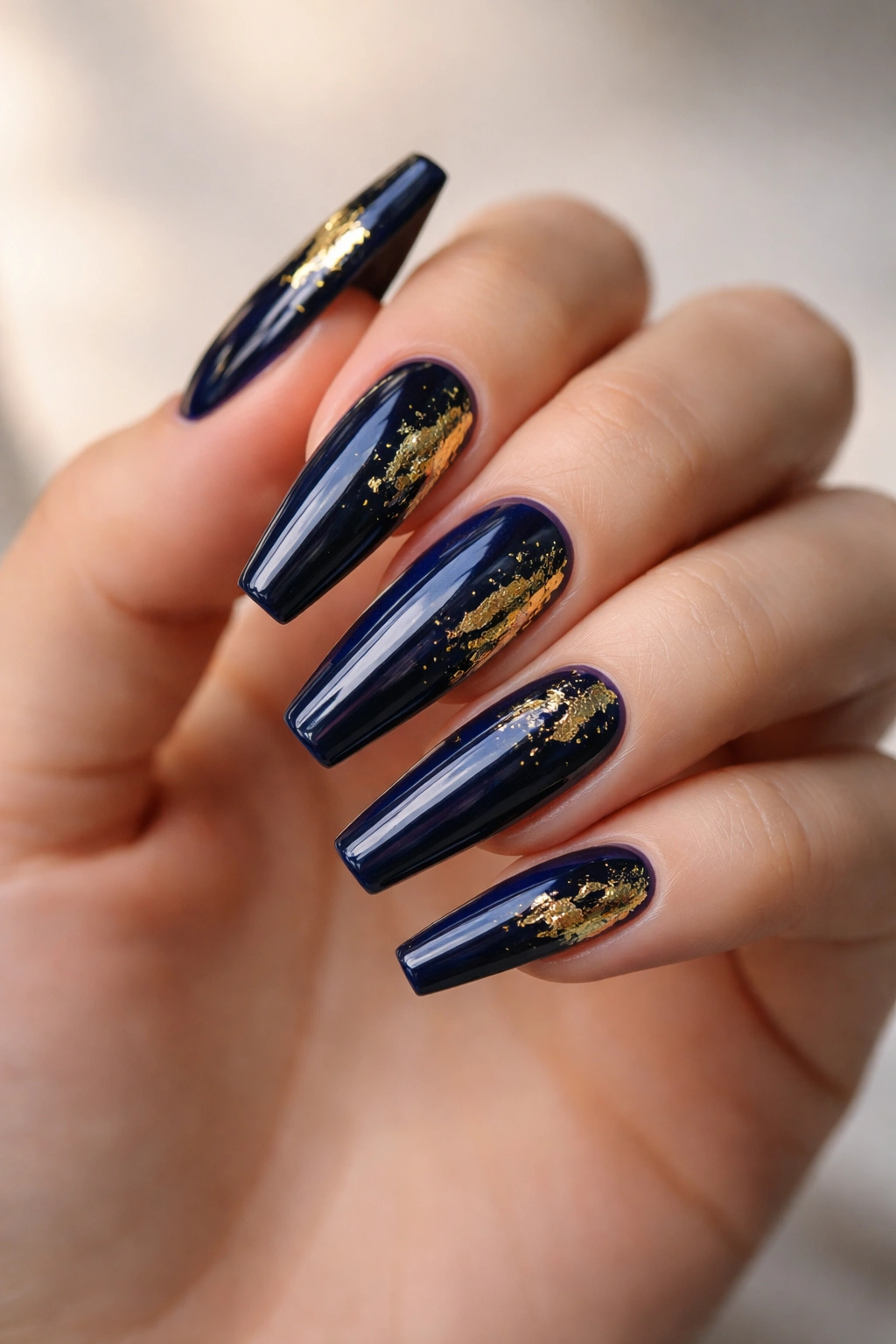 Navy blue coffin nails with gold foil accents reflecting light