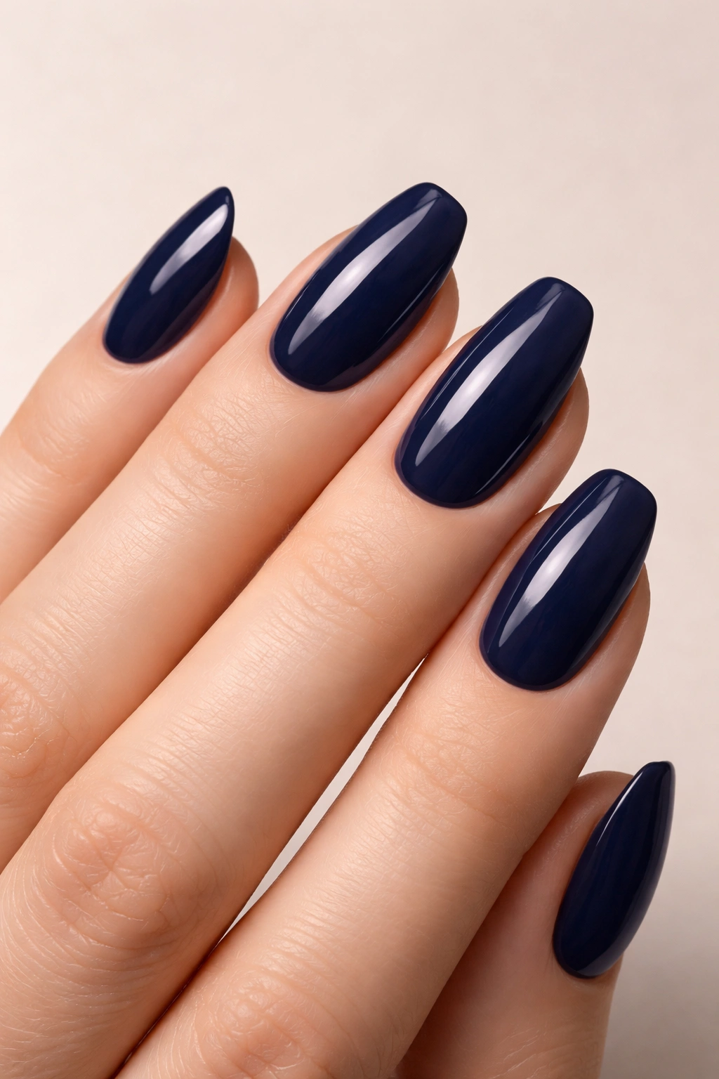 Close-up of navy blue nails with rich color on a neutral background