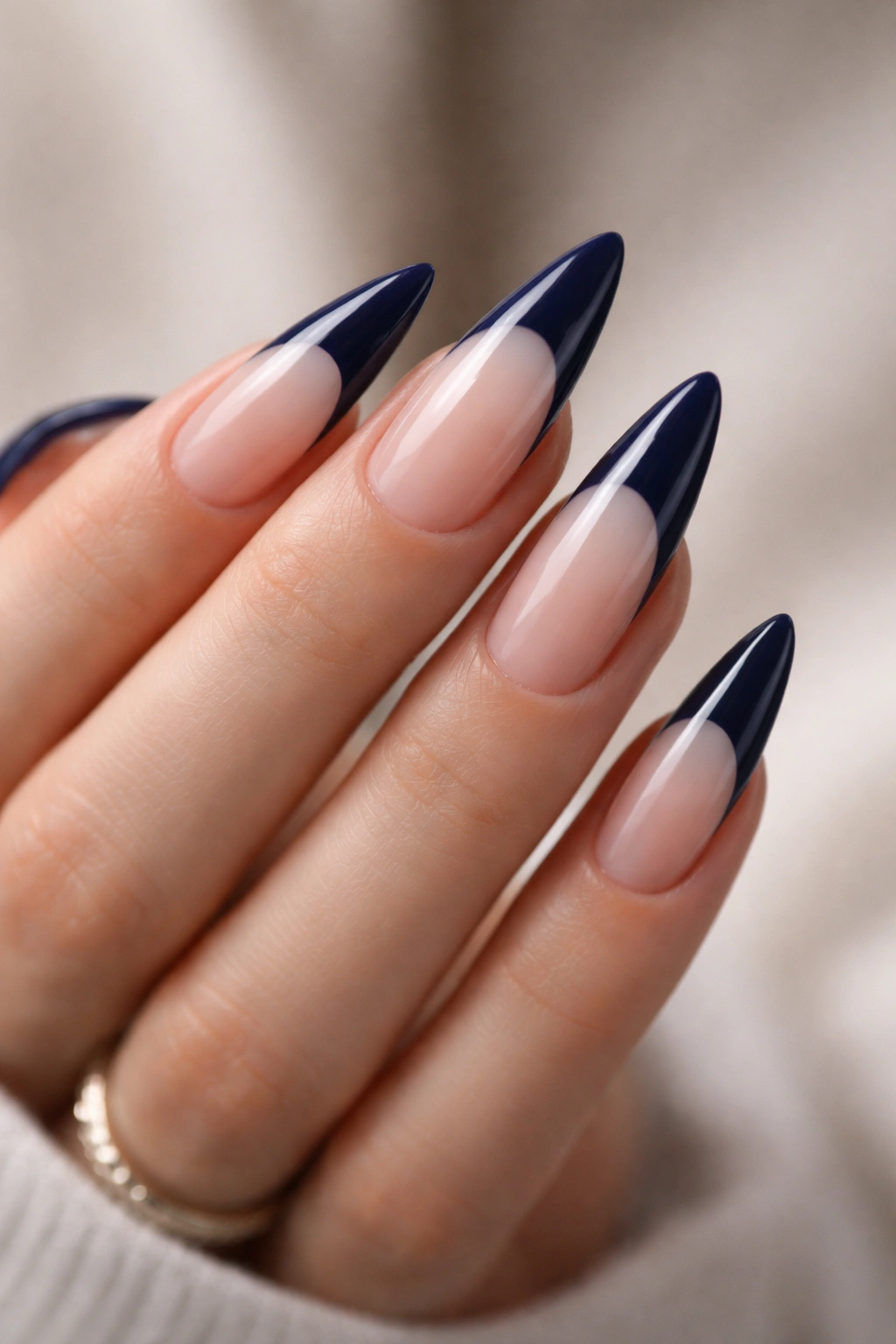 Close-up of navy blue French tip nails on stiletto shape with glossy finish