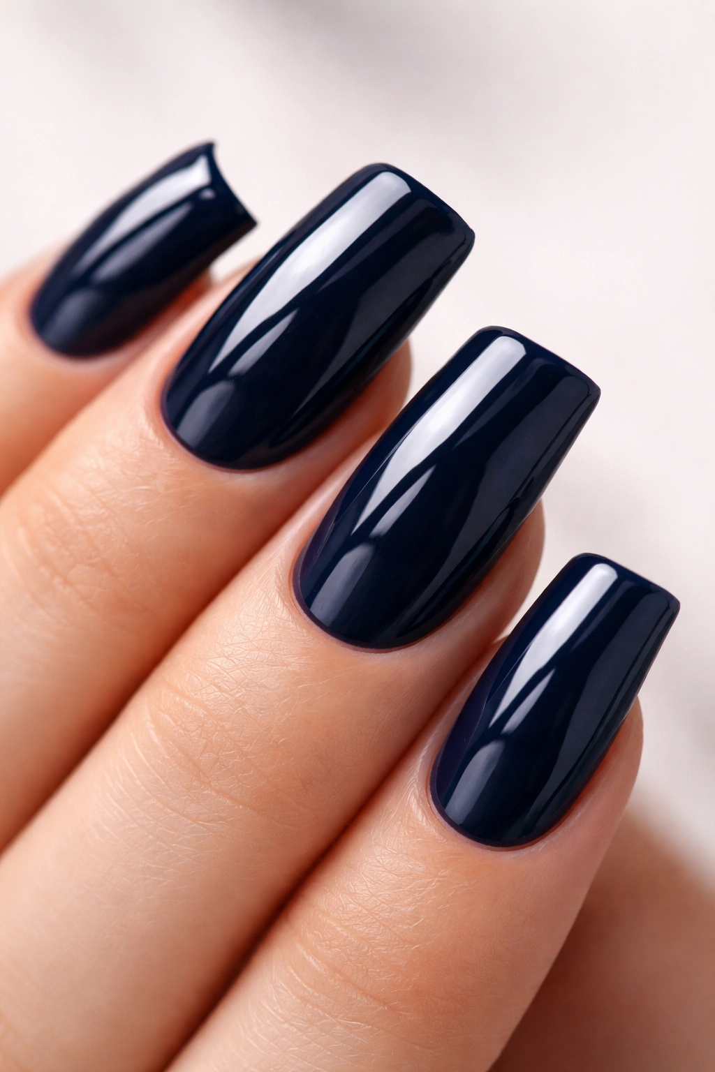 Close-up of navy blue duck nails with glossy finish emphasizing the curved tip.
