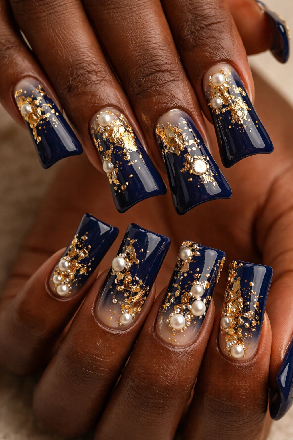 Navy duck nails with gold foil and pearls on dark skin