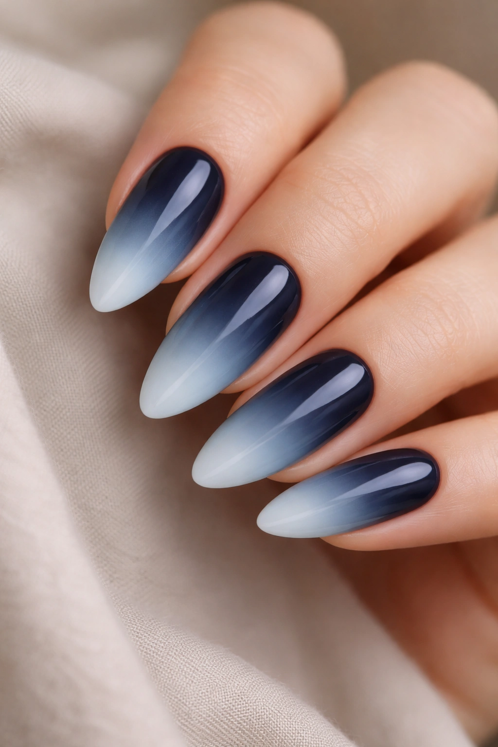 Almond nail gradient from navy base to ice blue tip.