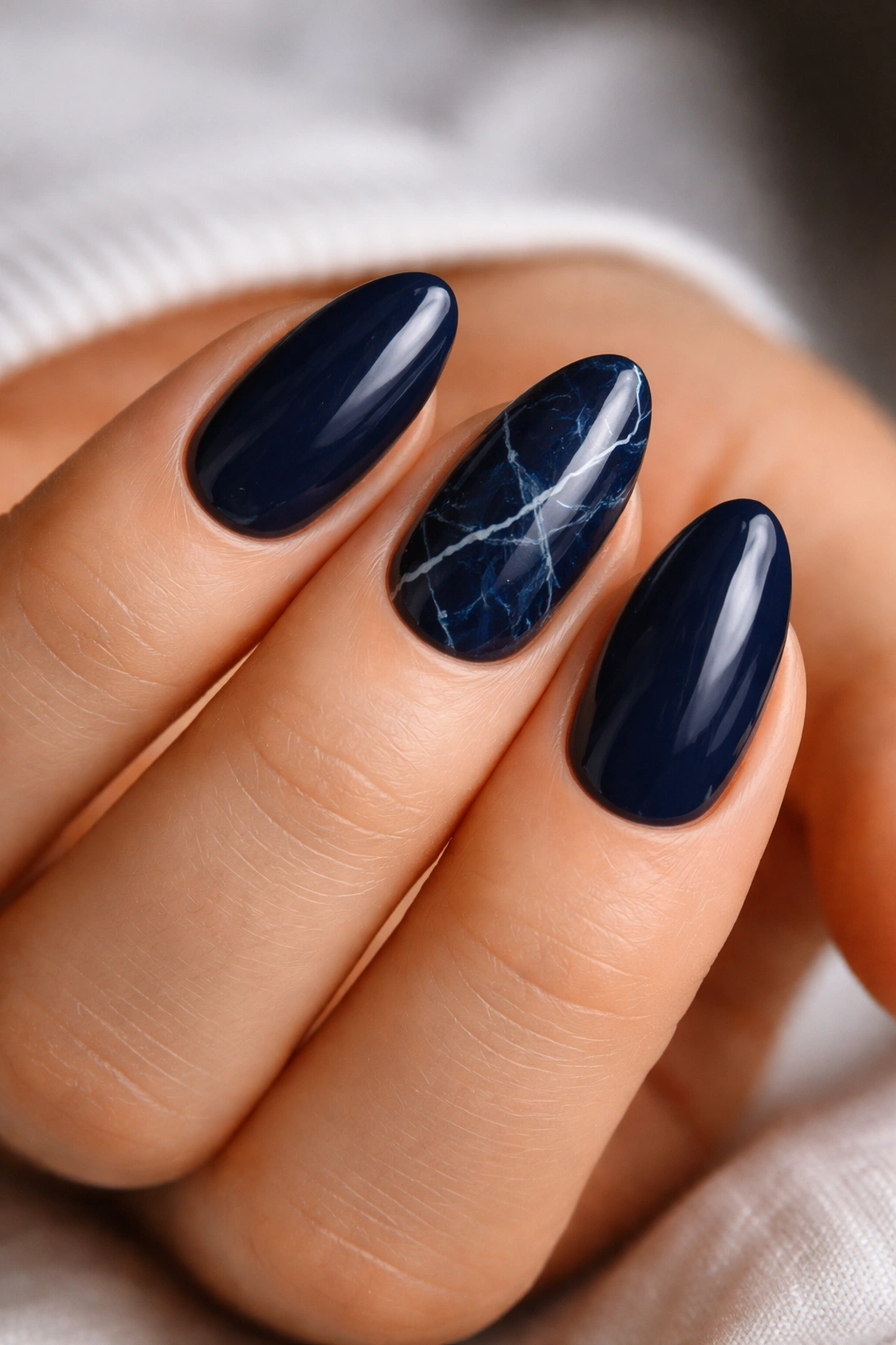 Navy nails with subtle white veining on two accent nails against a navy background.