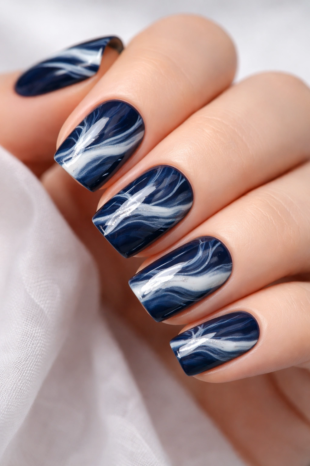 Close-up of navy and white marbled nails on fingertips