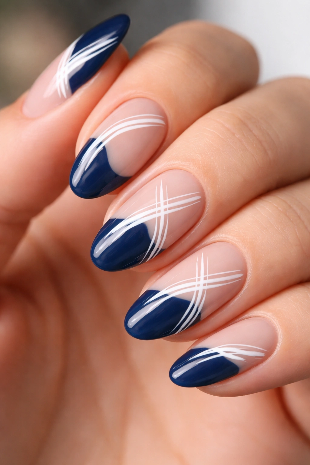 Close-up of short almond nail with navy tip and irregular white brushstroke lines