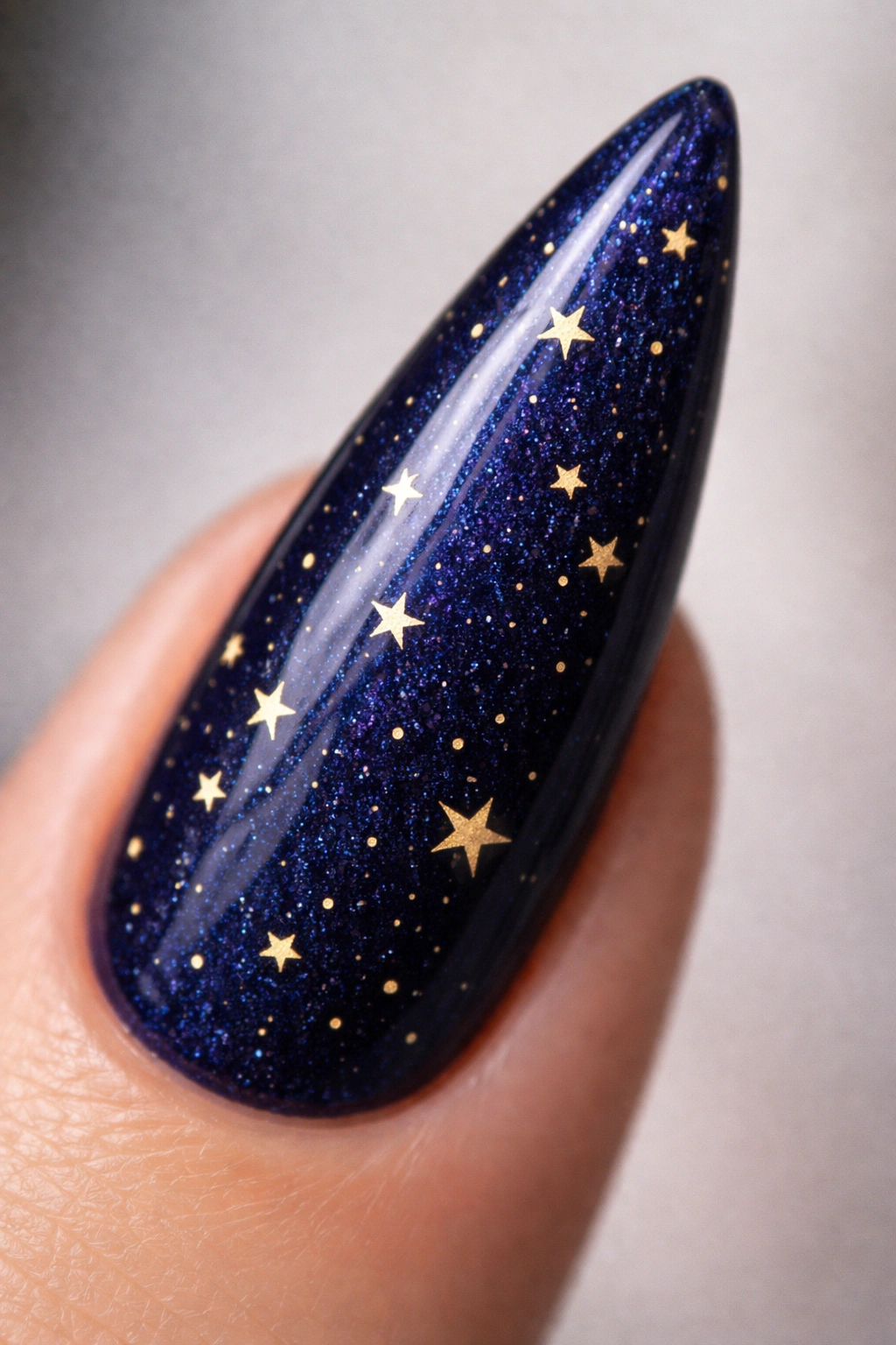 Stiletto nail navy blue with tiny gold stars close-up
