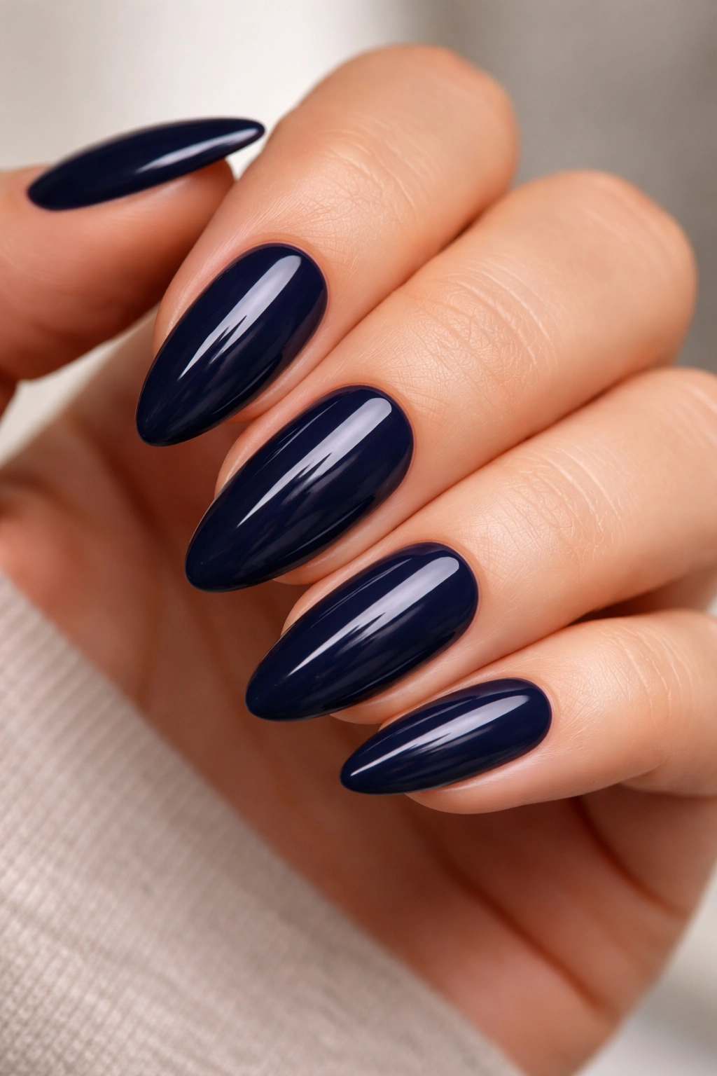 Close-up of deep navy almond nails with a glossy finish
