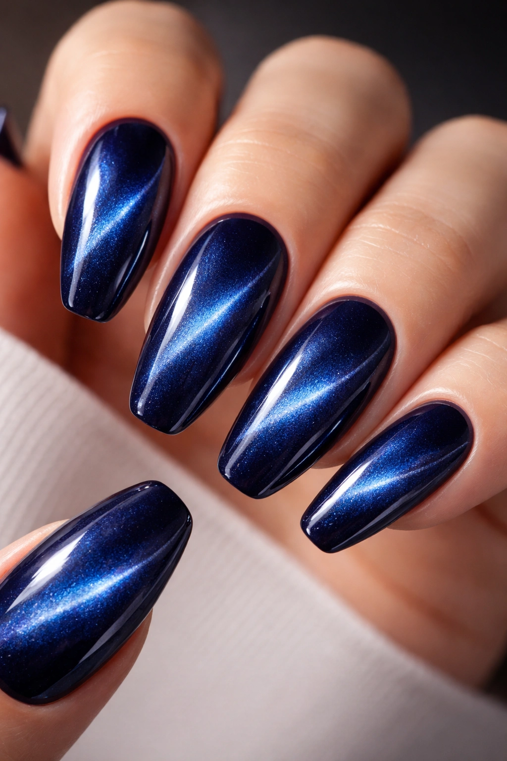 Navy cat-eye nails showing magnetic linear patterns
