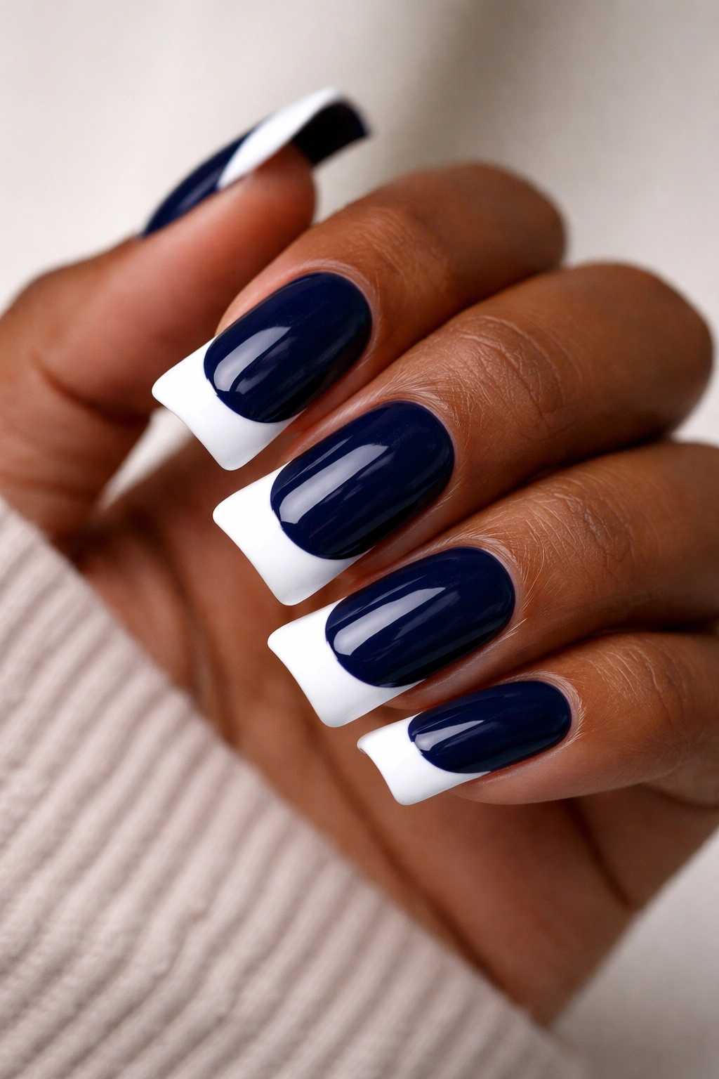 Close-up of navy nails with white duck-tip accents on dark skin