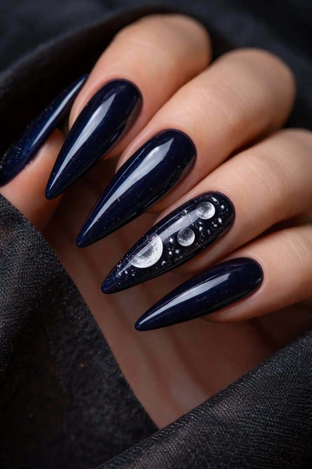 Close-up of dark navy nails with white and pale gold moon phases