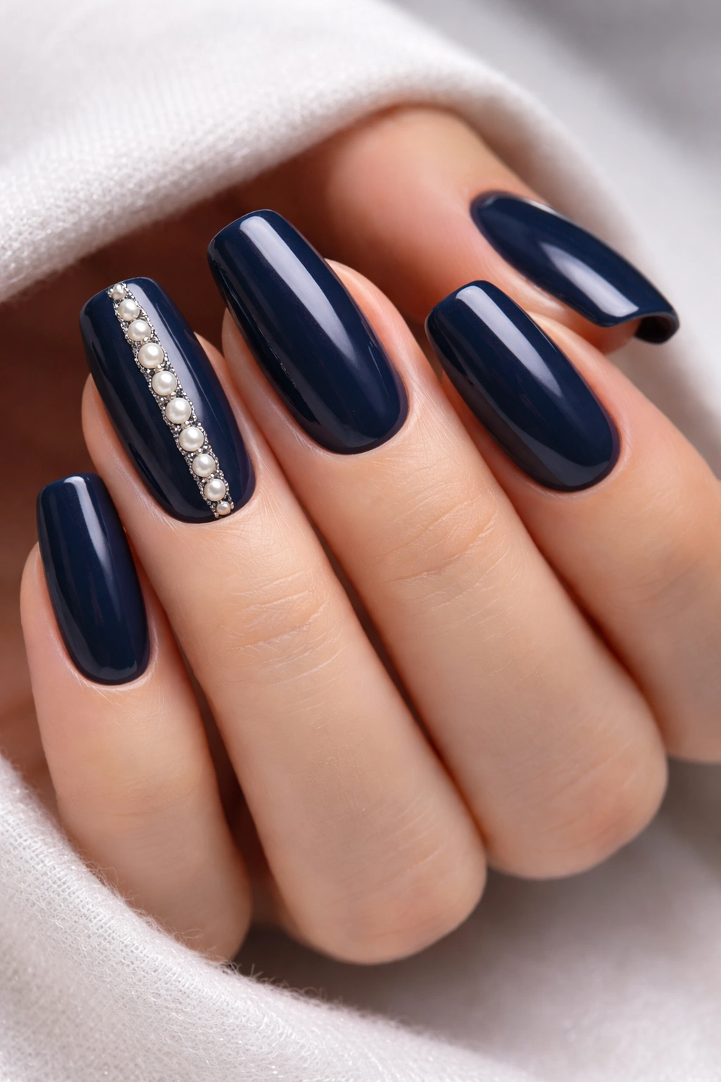 Navy rounded-square nails with delicate pearl inlay on one nail