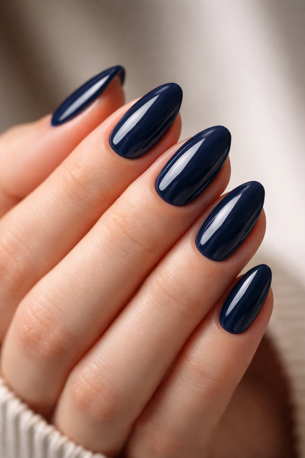 Close-up of navy blue short almond nails with glossy finish