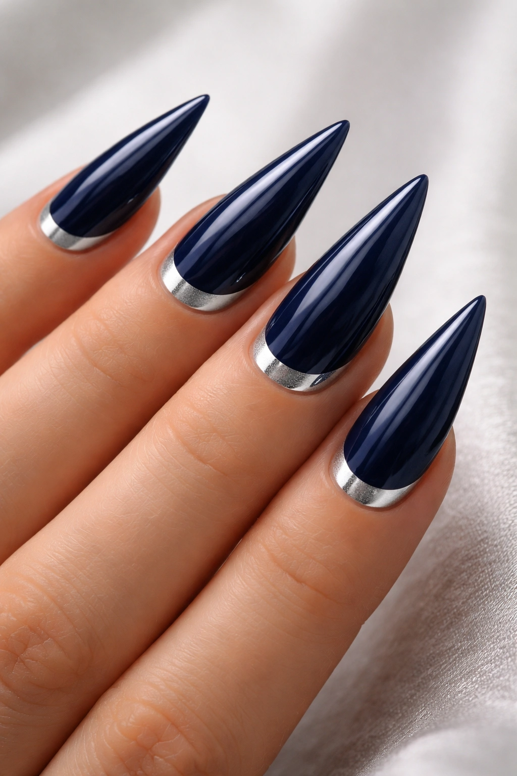 Navy nails with silver half-moon accent on stiletto shape