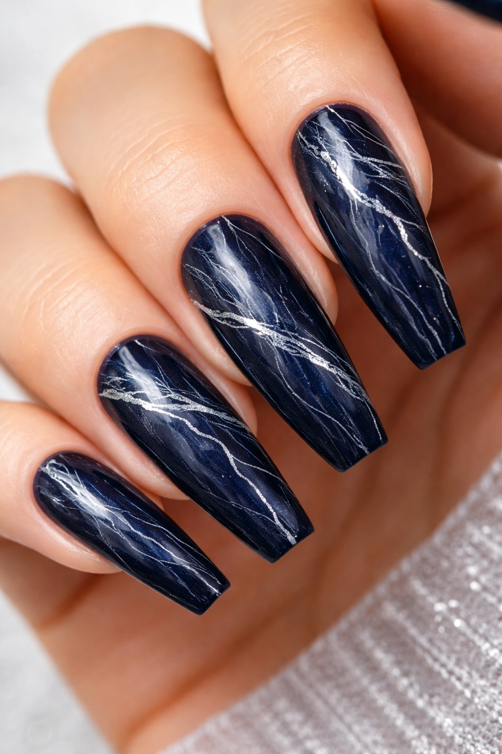 Close-up of navy nails with white and silver veining