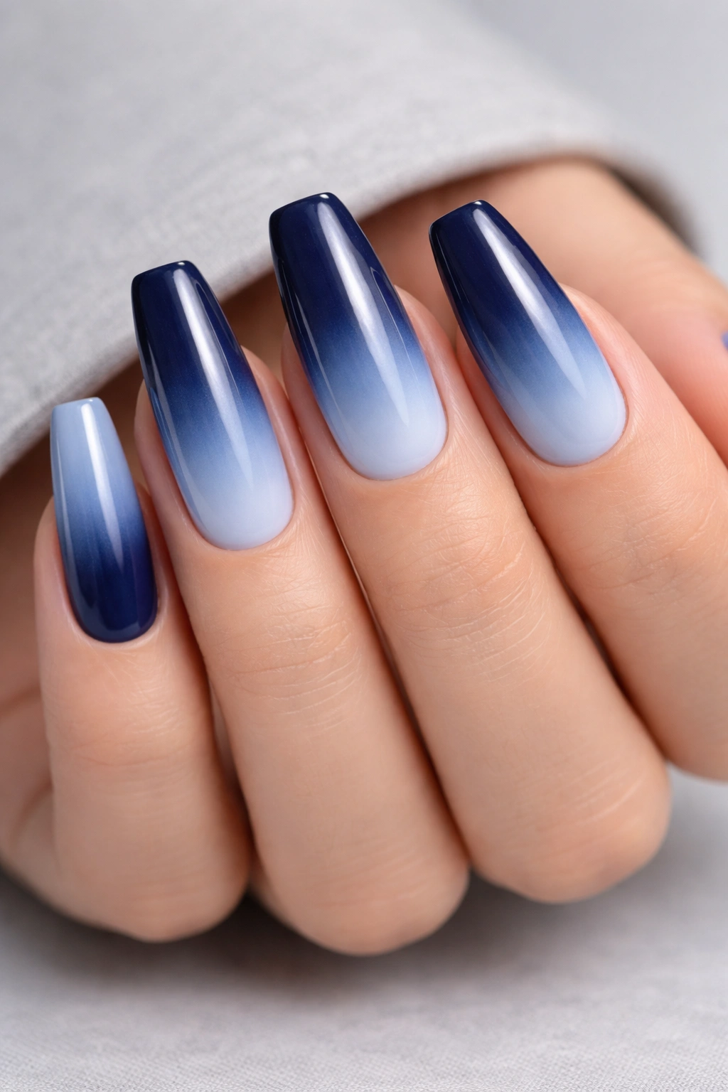 Close-up of navy to powder blue ombre nails on medium coffin shape