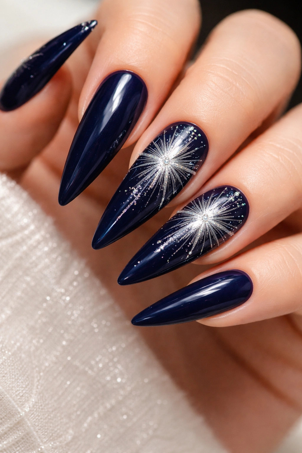 Dark blue nails with silver starburst accents on stiletto nails