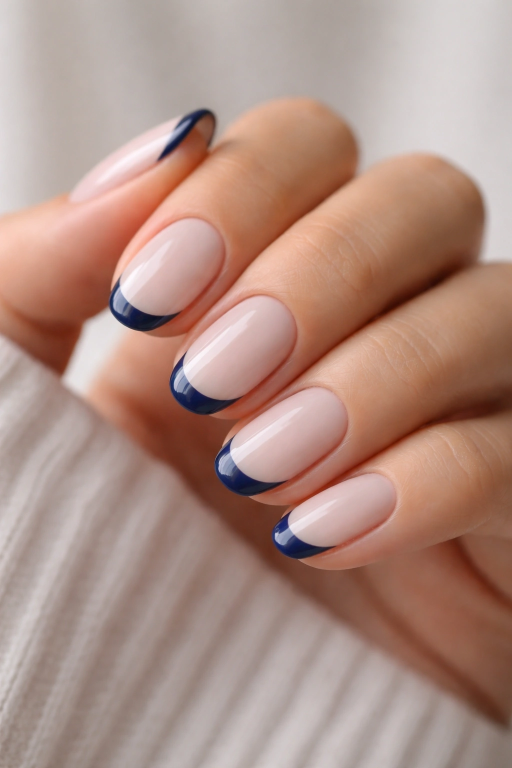 Navy French tips on milky base nails, short oval shape