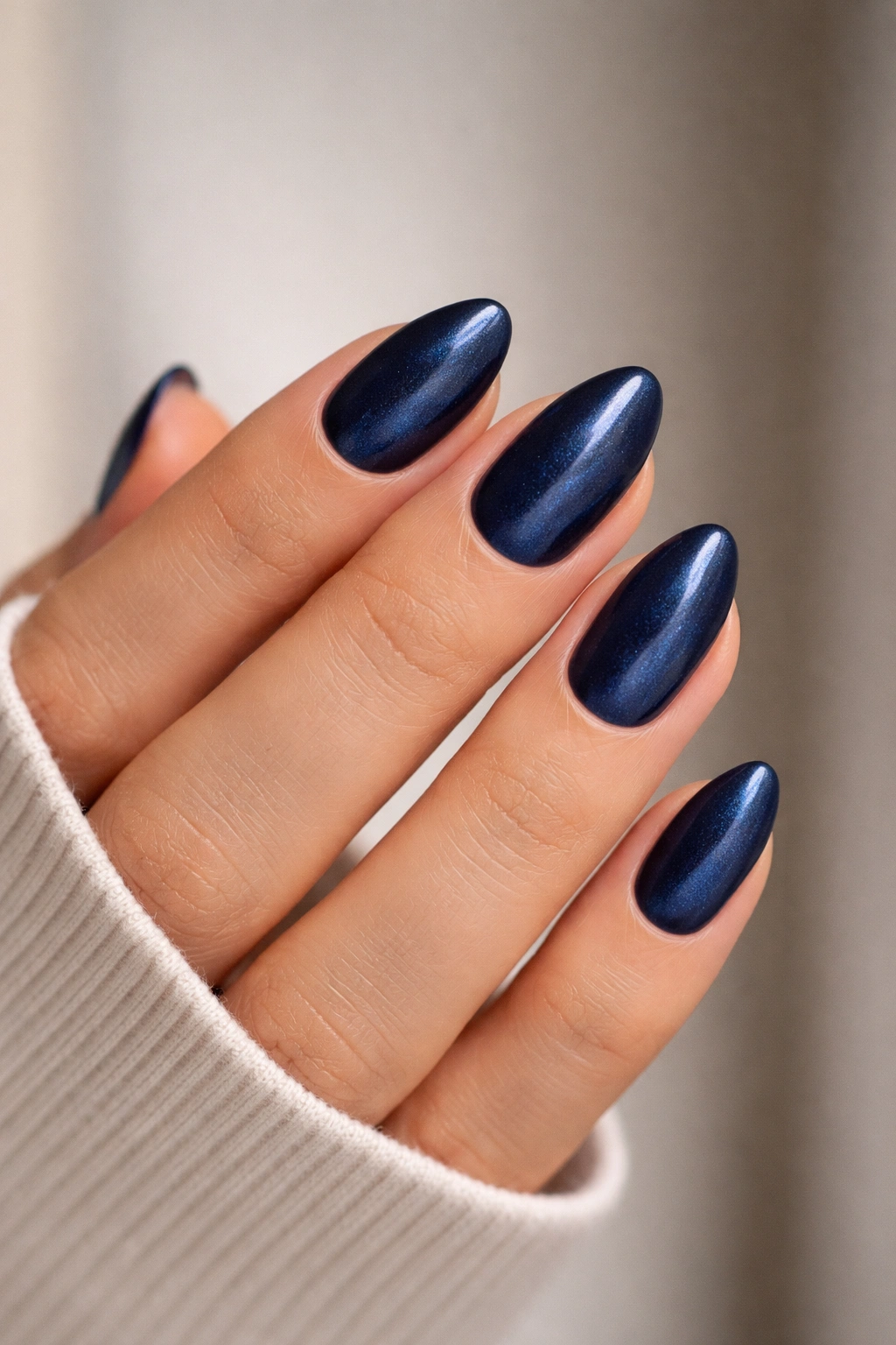 Close-up of navy almond nails with velvet finish and subtle light shift
